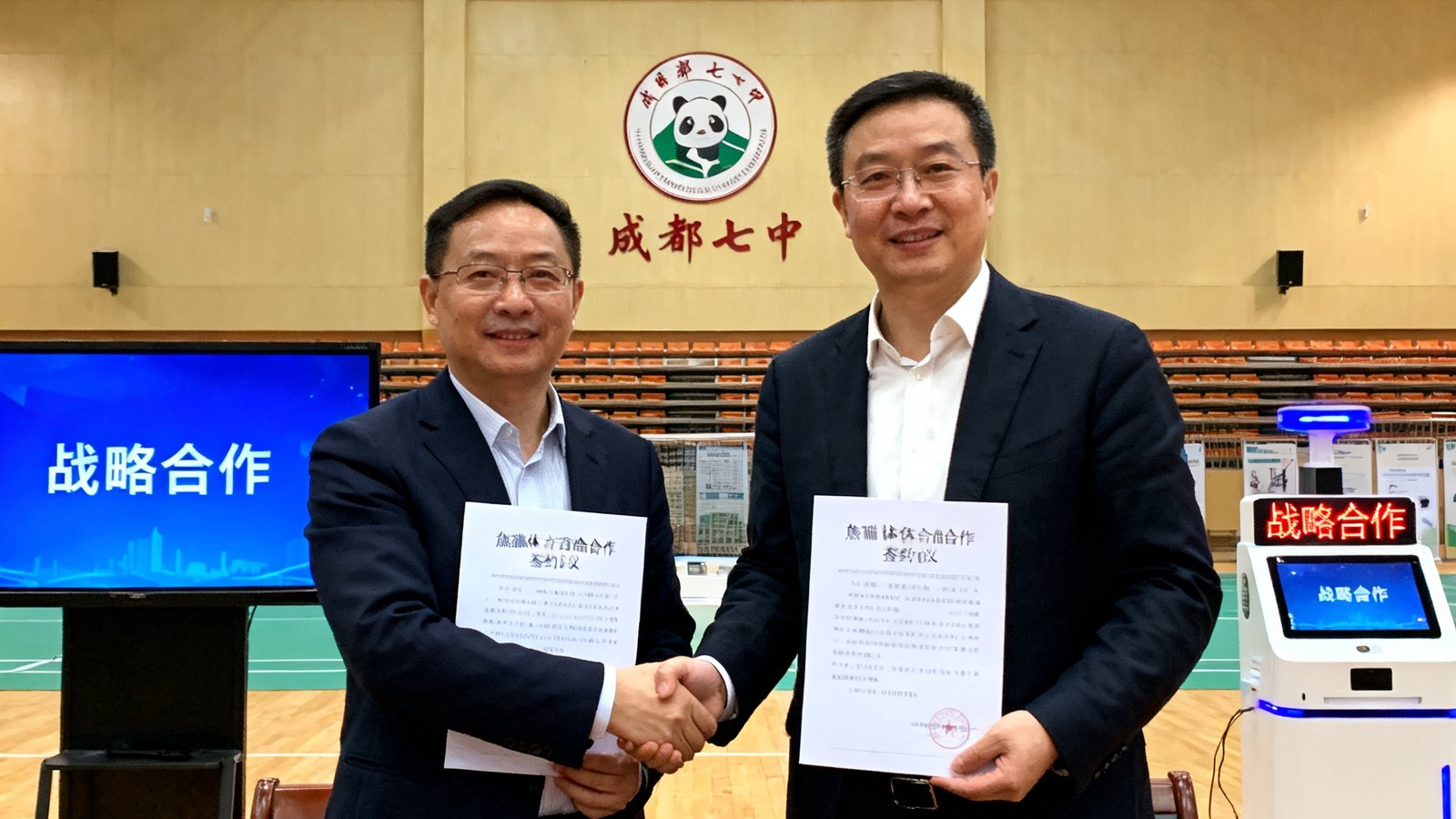 成都七中与熊猫体育战略合作签约仪式现场，双方代表握手并展示合作协议，背景是学校体育馆和智能设备展示区